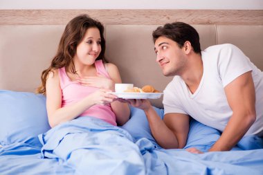 Mutlu bir aile yatakta kahvaltı yapıyor.