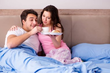 Mutlu bir aile yatakta kahvaltı yapıyor.