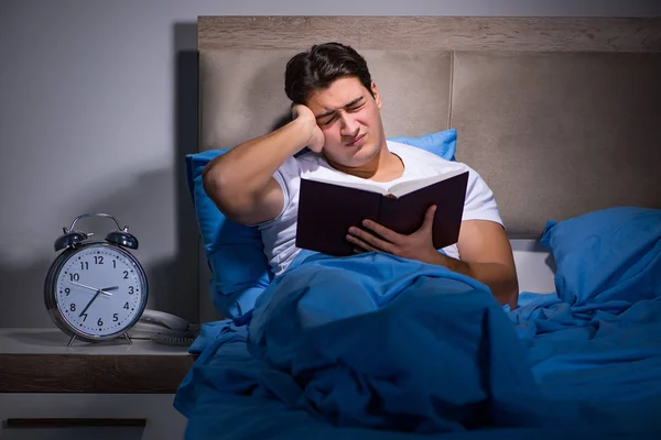 Giovane uomo lettura libro a letto — Foto Stock