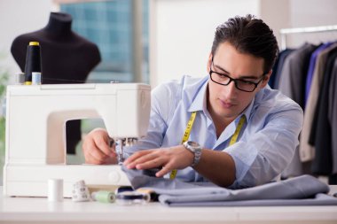 Genç terzi yeni elbiseler üzerinde çalışıyor.