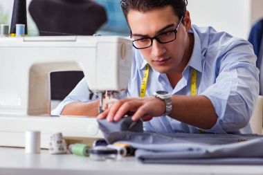 Genç terzi yeni elbiseler üzerinde çalışıyor.