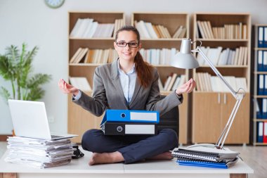 İş kadını ofiste meditasyon yapıyor.