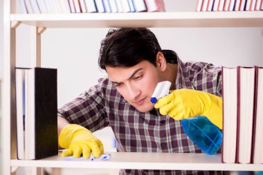 Kitaplıktaki tozları temizleyen adam