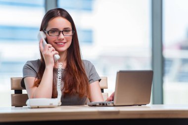 Genç bayan ofiste telefonla konuşuyor.