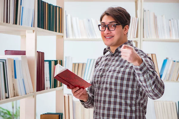 Молодой студент ищет книги в библиотеке колледжа — стоковое фото