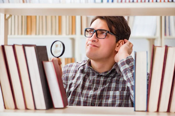 Mladý student hledá knihy v univerzitní knihovně — Stock fotografie