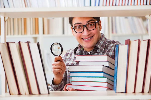 Giovane studente in cerca di libri nella biblioteca del college — Foto Stock