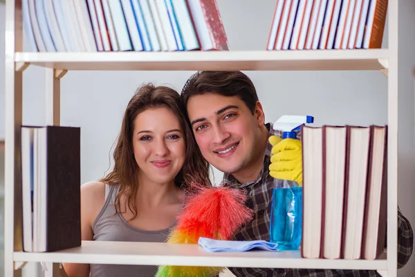 Feleség és férj port tisztít a könyvespolcról — Stock Fotó