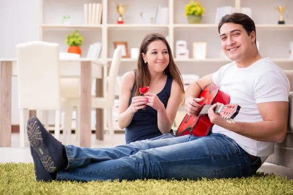 Романтическая пара, играющая на гитаре на полу — стоковое фото