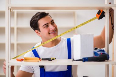 İşçi adam montaj kitaplığını tamir ediyor