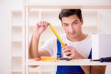 İşçi adam montaj kitaplığını tamir ediyor