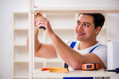 İşçi adam montaj kitaplığını tamir ediyor