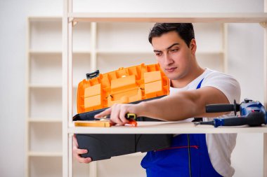 İşçi adam montaj kitaplığını tamir ediyor