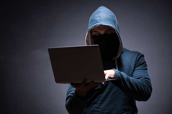 Хакер в капюшоне в темной комнате
