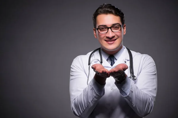 Junge Ärztin vor dunklem Hintergrund — Stockfoto