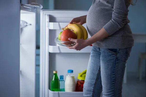 Terhes nő a hűtő közelében, ételt és harapnivalót keres éjszaka — Stock Fotó