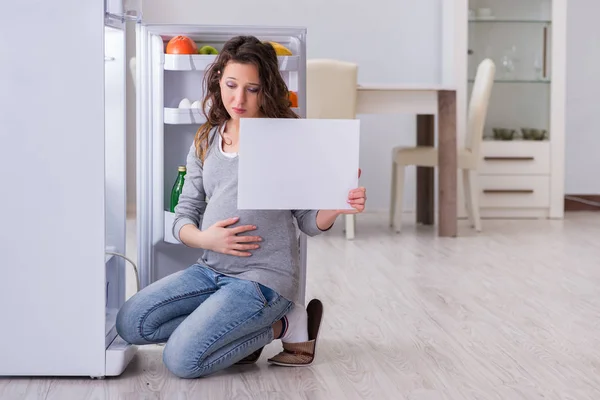 Беременная женщина возле холодильника с пустым сообщением — стоковое фото