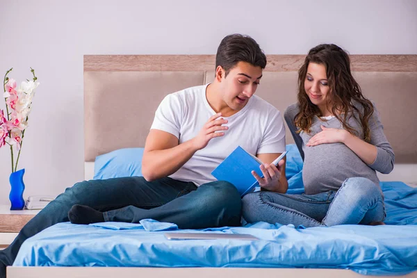 Ung familj med gravid fru väntar barn i sängen — Stockfoto