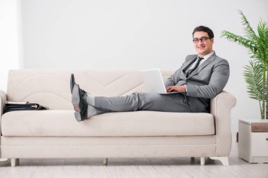 Genç işadamı kanepede yatıyor.