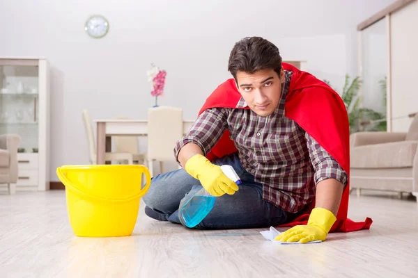 Super herói marido limpeza chão em casa — Fotografia de Stock