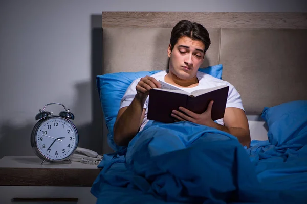 Jovem homem lendo livro na cama — Fotografia de Stock