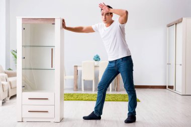 Genç adam evde mobilya taşıyor.