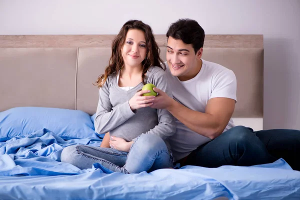 Νεαρή οικογένεια με έγκυο γυναίκα περιμένει μωρό στο κρεβάτι — Φωτογραφία Αρχείου