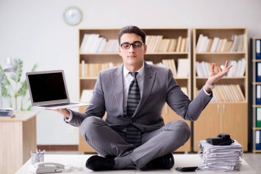 Genç işadamı ofiste meditasyon yapıyor.