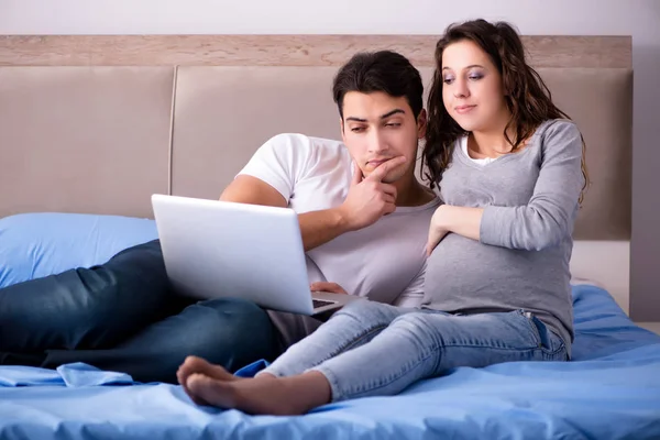 Familia joven con esposa embarazada esperando al bebé en la cama —  Fotos de Stock