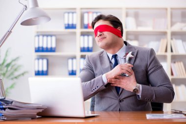 Ofiste masasında oturan gözü bağlı iş adamı.