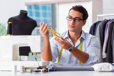 Genç terzi yeni elbiseler üzerinde çalışıyor.