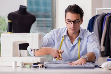 Genç terzi yeni elbiseler üzerinde çalışıyor.