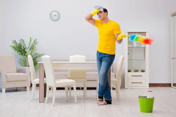 Чоловік прибирає будинок, допомагаючи дружині — стокове фото