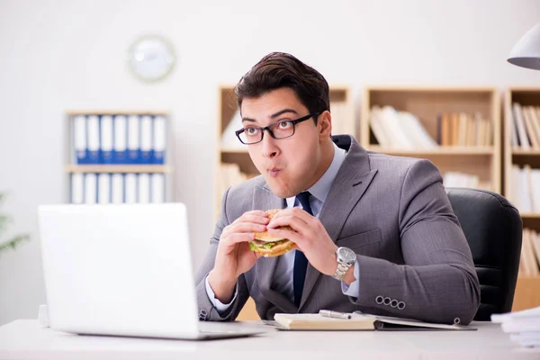 Hambriento empresario divertido comer sándwich de comida chatarra — Foto de Stock