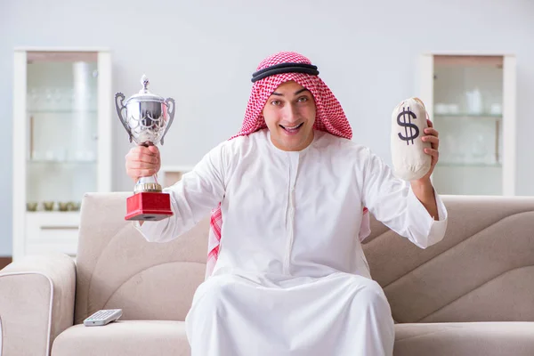 Arab man with prize and money on sofa — Stock Photo, Image