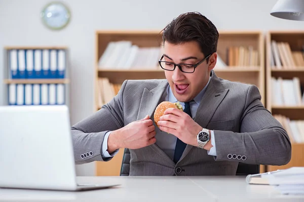 Hambriento empresario divertido comer sándwich de comida chatarra — Foto de Stock