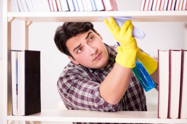 Kitaplıktaki tozları temizleyen adam