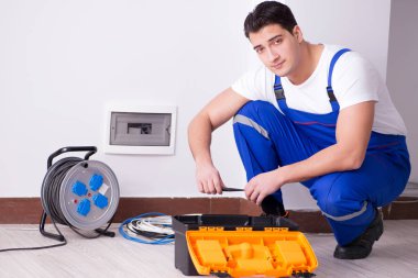 Genç elektrikçi evde soket üzerinde çalışıyor.