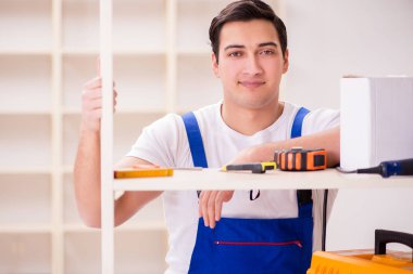 İşçi adam montaj kitaplığını tamir ediyor