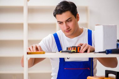 İşçi adam montaj kitaplığını tamir ediyor