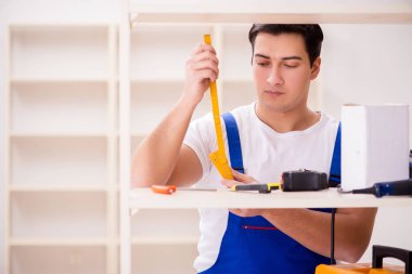 İşçi adam montaj kitaplığını tamir ediyor