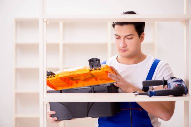 İşçi adam montaj kitaplığını tamir ediyor