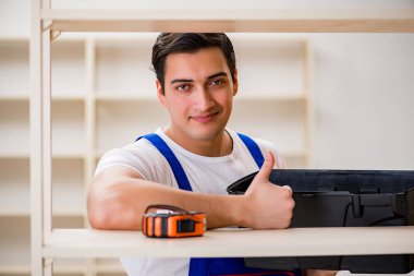 İşçi adam montaj kitaplığını tamir ediyor