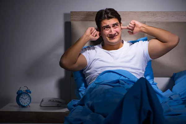 Junger Mann kämpft mit Lärm im Bett — Stockfoto