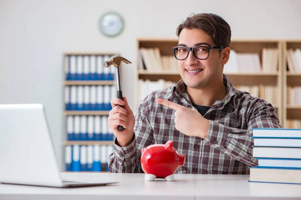 Young student breaking piggy bank to buy textbooks — Stock Photo, Image