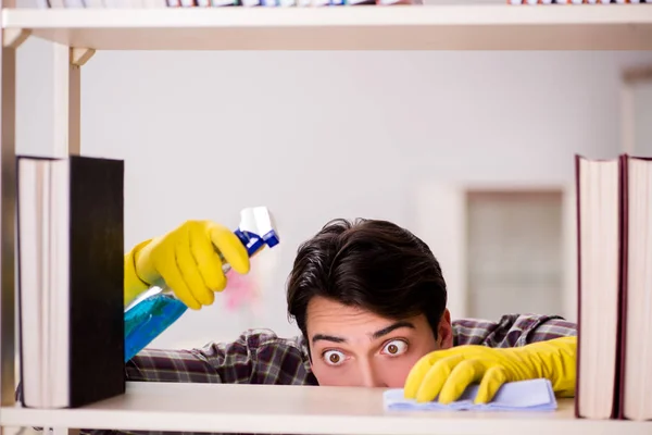 Hombre limpiando polvo de la estantería —  Fotos de Stock