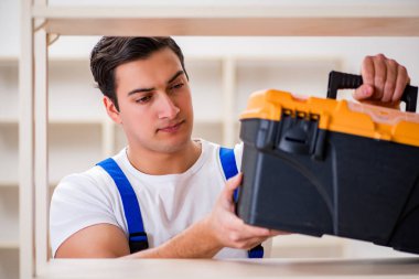 İşçi adam montaj kitaplığını tamir ediyor