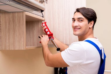 Genç adam mutfak mobilyalarını monte ediyor.