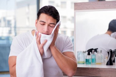 Genç yakışıklı adam yüz kremi sürüyor.