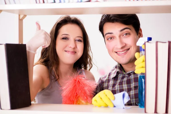 Esposa e marido limpando o pó da estante — Fotografia de Stock